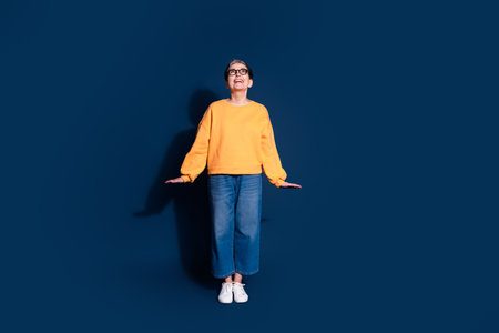 Full length photo of lovely pensioner lady look up empty space cute posing dressed stylish yellow garment isolated on dark blue backgroundの写真素材