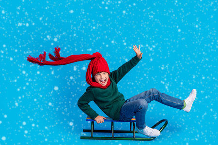 Full length body size photo boy shouting riding sledges isolated bright blue color backgroundの写真素材