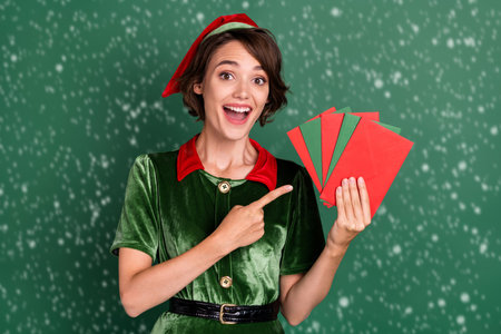 Portrait of attractive cheerful girl holding demonstrating letters eve day time isolated over green color backgroundの写真素材