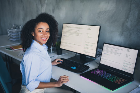 Photo of cheerful positive lady dressed shirt programming modern gadget indoors workplace workstation loftの写真素材
