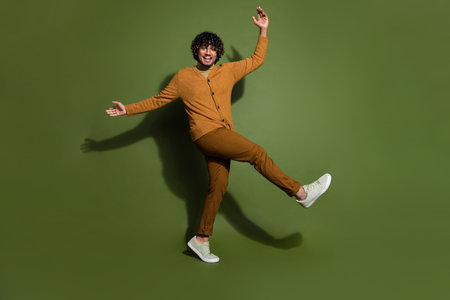 Full body photo of pretty young male dancing have fun wear trendy brown outfit isolated on khaki color backgroundの写真素材