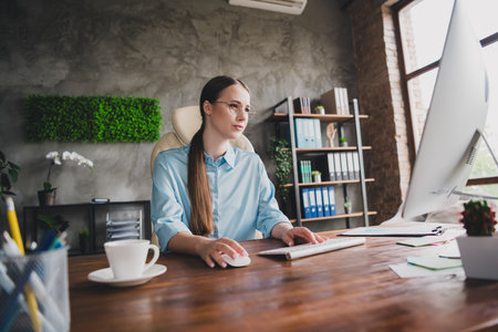 Photo of sweet charming lady assistant wear shirt glasses browsing modern gadget indoors workplace workstationの写真素材