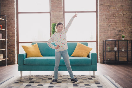 Full length portrait of charming little girl show v-sign wear pullover modern interior flat indoorsの写真素材