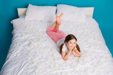 Photo of pretty lovely cute dreamy girl lying comfortable bed isolated on blue color backgroundの写真素材