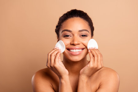 Photo of gorgeous cheerful woman apply sponge tonic naked shoulders isolated on beige pastel color backgroundの写真素材