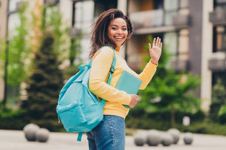 Photo of charming positive cute girl wear yellow trendy clothes going lesson hello sign spring day...