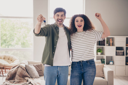 Photo of two young people raise fists show hold key modern interior apartment indoorsの写真素材