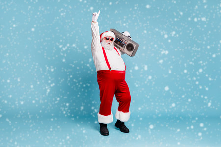 Full length body size view of his he nice cool stylish cheerful Santa big belly pants carrying vintage cassette player dancing isolated on bright vivid shine vibrant blue turquoise color backgroundの写真素材