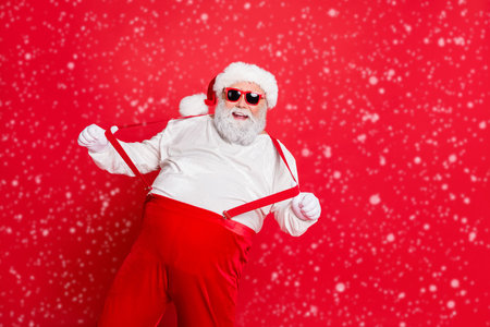 Ho-ho-ho holly jolly noel Photo of cheerful laughing grandfather pulling holding boasting suspenders on trousers having fun time on vacation weekend isolated bright backgroundの写真素材