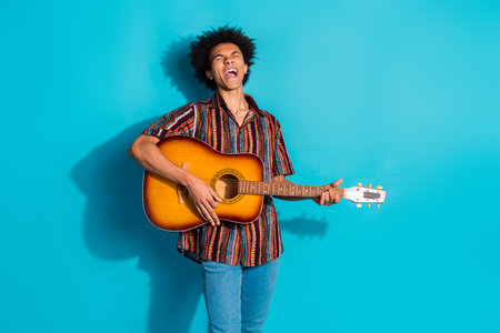 Photo of nice young man play guitar singing wear shirt isolated on teal color backgroundの写真素材