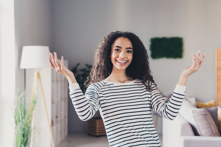 Photo of nice young girl raise hands excited have fun wear striped clothes enjoy modern cozy interior flat indoorsの写真素材