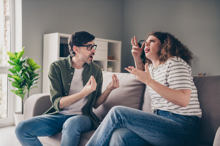 Photo of two young people sitting couch communicate fight modern interior apartment indoorsの写真素材