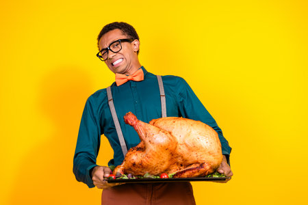 Photo of guy hold big turkey for thanksgiving day spoiled dislike smell isolated yellow color backgroundの写真素材