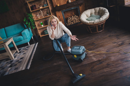 Photo of stressed depressed lady wear white shirt doing daily cleaning calling service modern device indoors room home houseの写真素材