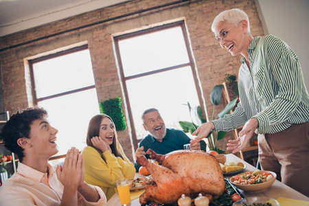 Photo of happy family excited eat turkey celebrate thanksgiving holiday dinner relatives living room celebrate weekendの写真素材