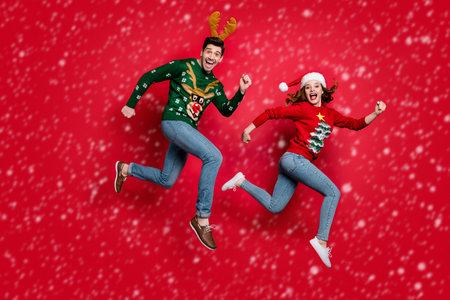 Full length photo of crazy jumping couple excited by x-mas discounts prices wear ugly ornament...
