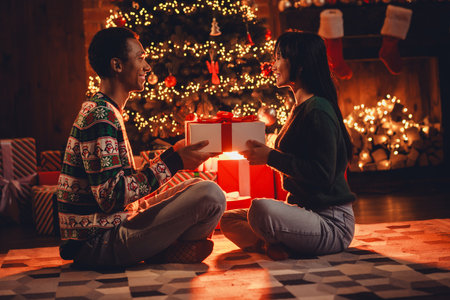 Full body photo of nice young couple give giftbox wear christmas clothes enjoy cozy x-mas party decoration interior flat indoorsの写真素材