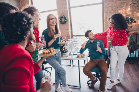 Photo of attractive young people employees drink champagne eat snacks new year decoration interior corporate party office