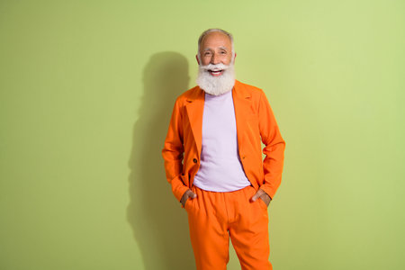 Photo of cheerful handsome nice retired man wear stylish suit isolated on green color backgroundの写真素材