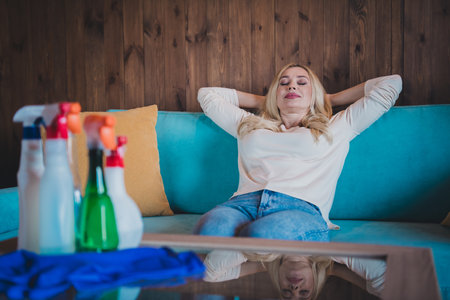 Photo of adorable sweet lady wear white shirt having rest arms behind head doing daily cleaning indoors room home houseの写真素材