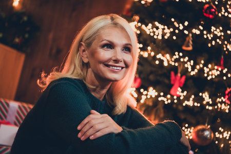 Photo of pretty retired woman look dreamy empty space dressed christmas garment tradition atmosphere decor house indoors roomの写真素材
