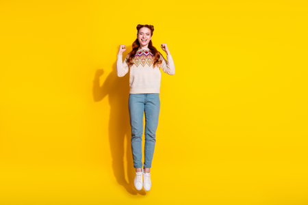 Photo portrait of attractive young woman jump raise fists celebrate dressed stylish knitted warm...