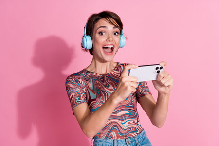 Photo of charming glad girl wear stylish clothes play online video game isolated on pink color...