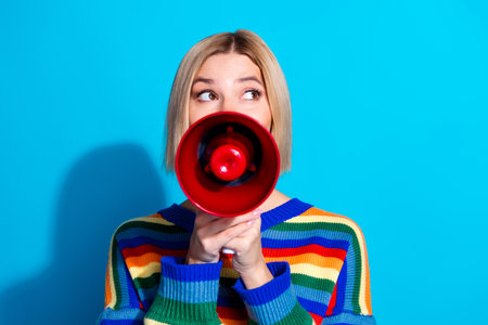Photo of nice young woman loudspeaker look empty space wear striped sweater isolated on blue color backgroundの写真素材