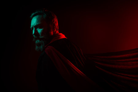 Photo of mysterious retired man evil wizard turn around back cape halloween costume isolated dark red green neon light backgroundの写真素材