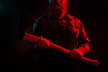 Photo of halloween male character furious man killer maniac hold sharp ax isolated on dark misty mysterious backgroundの写真素材