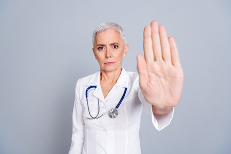 Photo of beautiful woman qualified specialist surgeon stop sign isolated on grey color backgroundの写真素材