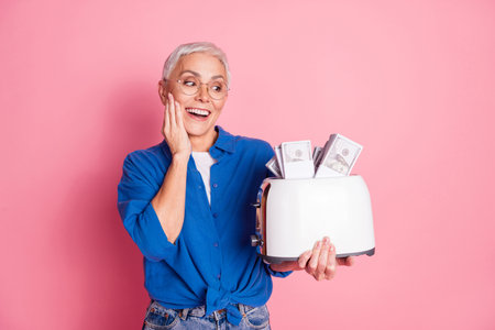 Photo of excited attractive lady dressed blue shirt toasting money empty space isolated pink color backgroundの写真素材