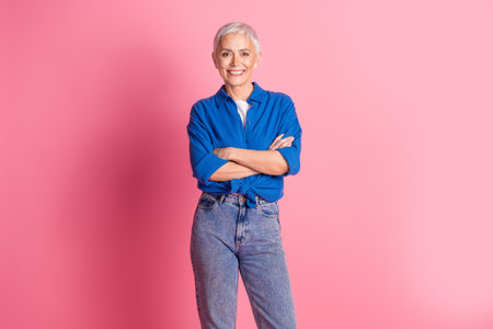 Photo of cheerful pretty lady dressed blue shirt smiling arms folded empty space isolated pink color backgroundの写真素材