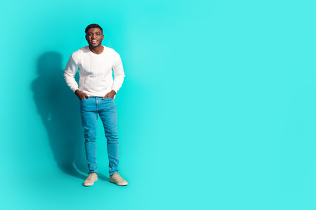 Full body photo of attractive young man posing hands pockets dressed stylish white clothes isolated on cyan color backgroundの写真素材
