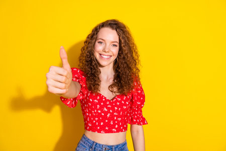 Photo of cheerful pretty lady dressed red blouse showing you thumb up empty space isolated yellow...