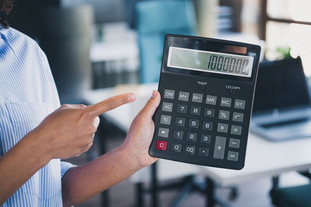 Photo of lady specialist dressed shirt pointing finger calculator indoors workstation workshopの写真素材