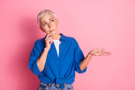 Photo of unsure uncertain lady dressed blue shirt holding medicine looking empty space isolated pink color backgroundの写真素材