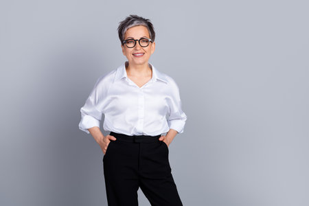 Portrait of elegant aged lady office worker posing empty space wear shirt isolated on grey color backgroundの写真素材