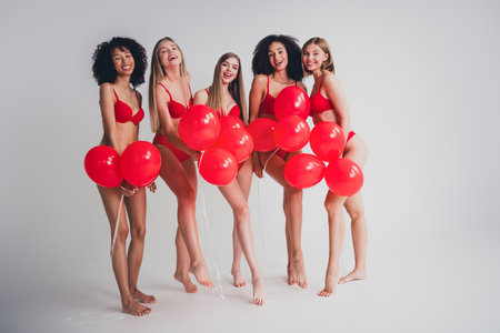 Full length photo of ladies people posing hold air balloons dressed red lingerie white wall studio background no filter self acceptanceの写真素材