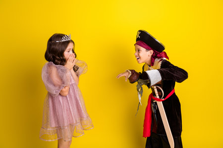 Photo of two kids halloween princess pirate costume scare boo isolated on yellow color backgroundの写真素材
