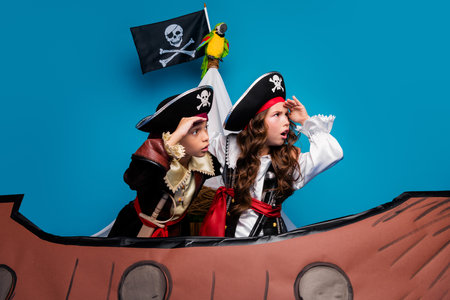 Photo portrait of cute little boy girl amazed adventure dressed pirates costumes float ship decor isolated on blue color backgroundの写真素材