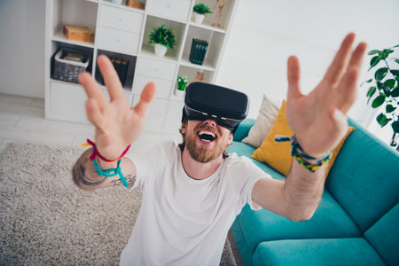 Photo of handsome young guy funky catch hands play vr game dressed nightwear spend pastime spacious...