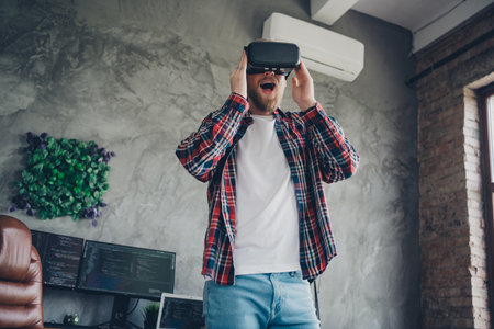 Photo of entertainment in loft modern design living room young overjoyed gamer guy wearing 3d...