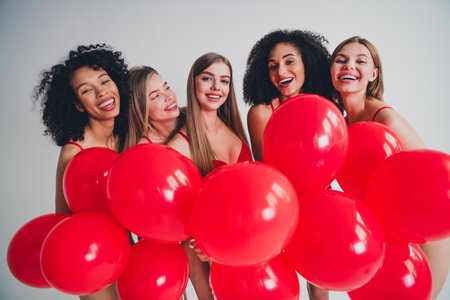 Photo of attractive young girls models hold air balloons wear red fashion lingerie isolated white wall background no filterの写真素材