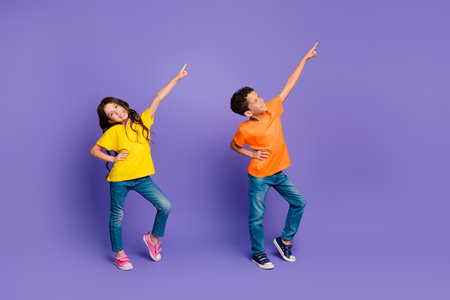 Full size photo of two small kids direct fingers empty space isolated on violet color backgroundの写真素材