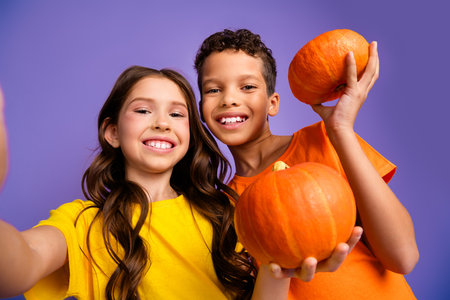 Photo portrait of cute little boy girl hold pumpkins dressed stylish yellow orange clothes isolated on purple color backgroundの写真素材