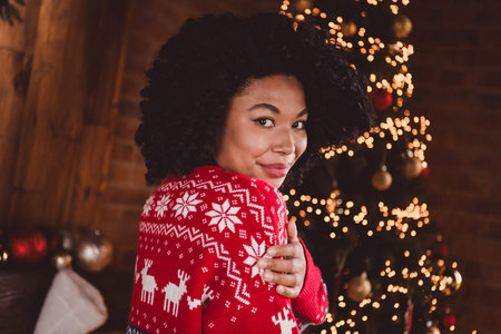 Photo of nice young girl hugging self wear red christmas clothes enjoy modern cozy x-mas party decoration interior flat indoorsの写真素材