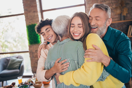 Photo of cheerful family hugging have fun congratulate meeting eating thanksgiving holiday dinner good mood having fun at home indoorsの写真素材