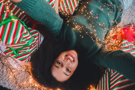 Photo of cute pretty girl hold gift box lying floor taking selfie cosy christmas atmosphere new year miracle indoors homeの写真素材