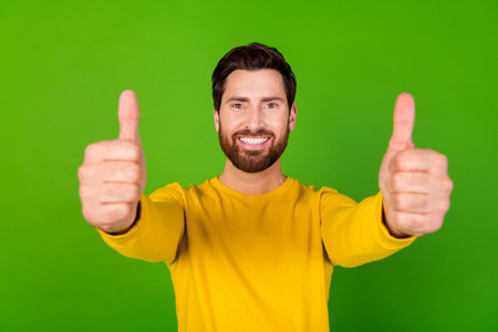 Photo of optimistic man with stylish beard dressed yellow shirt showing you thumbs up approve good...